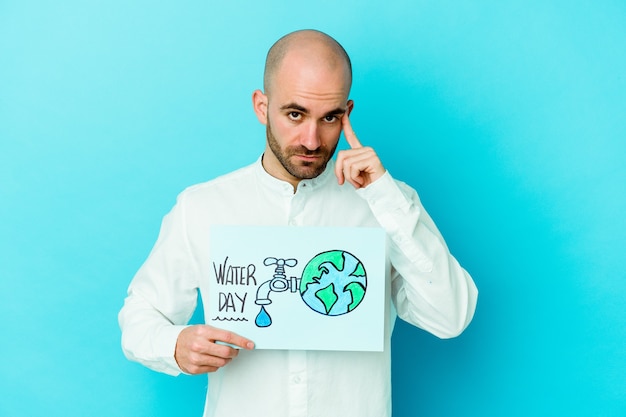 Jovem careca caucasiano comemorando o dia mundial da água, isolado sobre fundo azul.