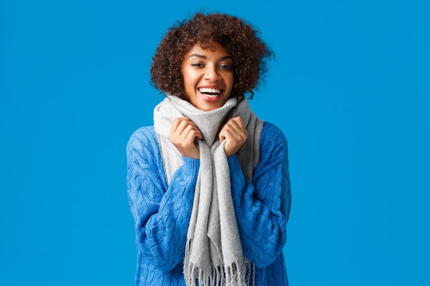 Foto jovem carismática adorável comprou roupas de inverno a tempo, embrulhar-se em lenço para se aquecer