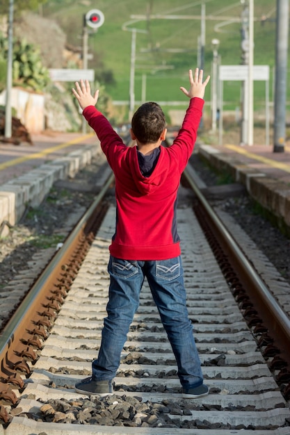 Jovem caroneiro esperando o trem parado na estrada de ferro