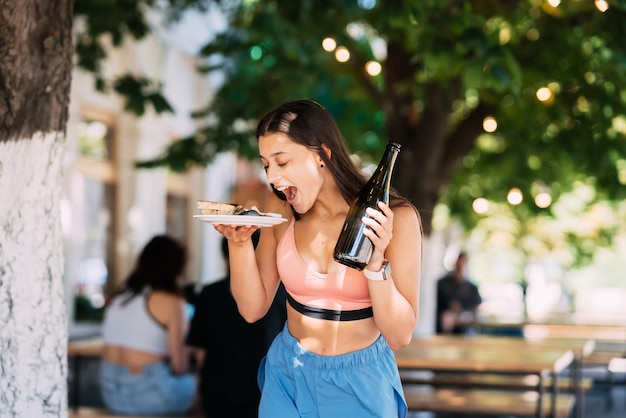 Jovem carrega um prato de lanches e uma bebida nas mãos