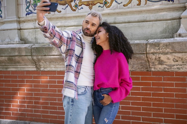 Jovem casal abraçando e tirando uma selfie no parque