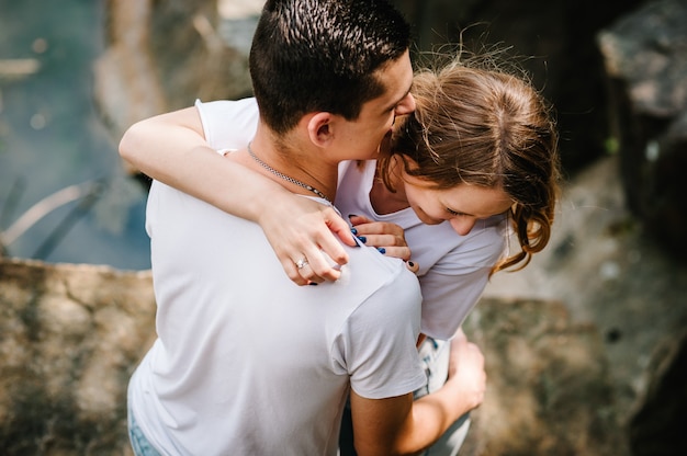 Jovem casal abraçando uma pedra perto do lago