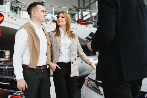 Jovem casal acompanhando um carro em um showroom de carros