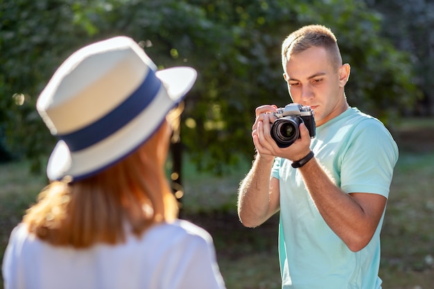 Jovem casal adolescente tirando fotos um do outro ao ar livre no parque ensolarado de verão.