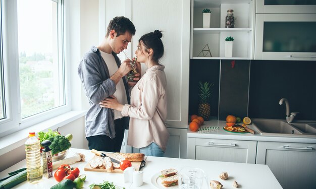 Jovem casal adorável bebendo mojito enquanto preparava o jantar na cozinha