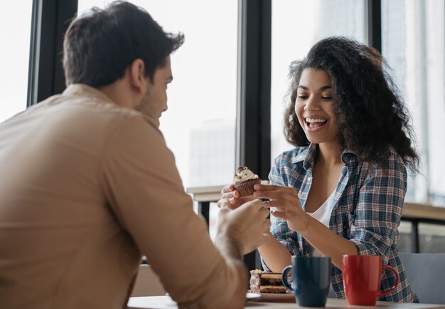 Jovem casal adorável comendo, rindo, comunicação juntos no café