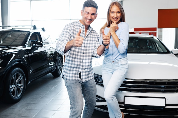 Jovem casal adorável na concessionária comprando um carro novo