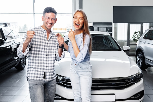 Jovem casal adorável na concessionária comprando um carro novo