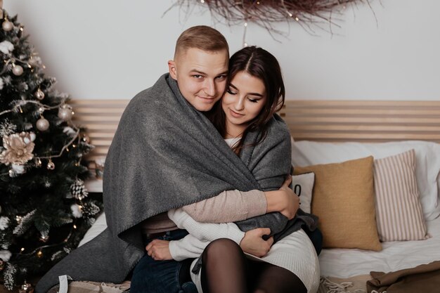 Jovem casal adorável sentado na cama se beijando e se abraçando