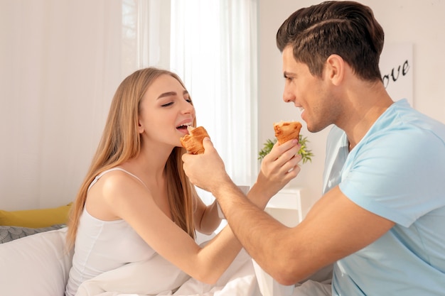 Jovem casal adorável tomando café da manhã na cama