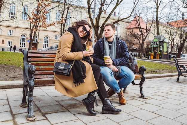 Jovem casal adulto comendo fast food no banco do parque da cidade