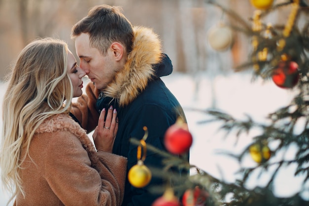 Jovem casal adulto decora a árvore de Natal na floresta de inverno. Conceito de celebração da festa de férias de pinho de ano novo.