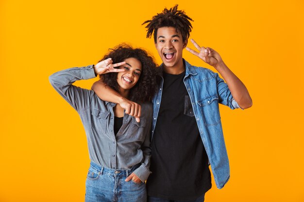 Jovem casal africano feliz vestindo roupas casuais, isolado, mostrando um gesto de paz