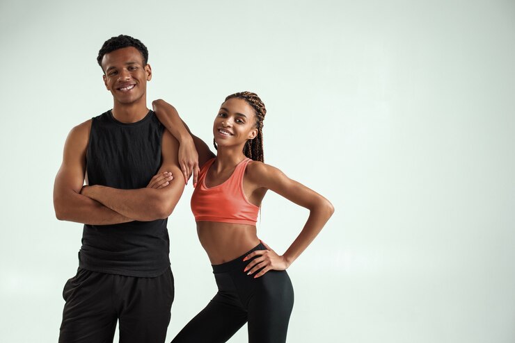 Jovem casal africano fitness esportivo e saudável em roupas esportivas, olhando para a câmera e sorrindo enquanto
