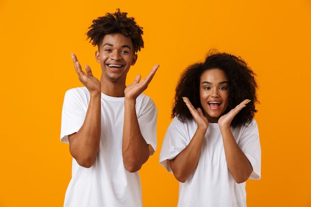 Jovem casal africano fofo emocional posando isolado sobre o espaço amarelo.