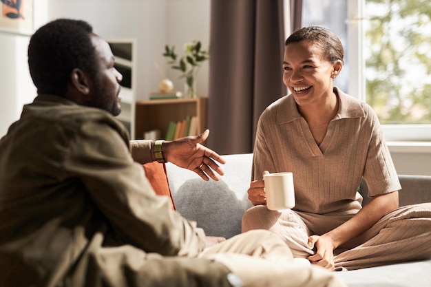 Jovem casal afro-americano aproveitando a conversa pela manhã em uma casa aconchegante