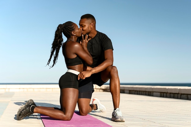 Jovem casal afro-americano beijando na praia perto da água