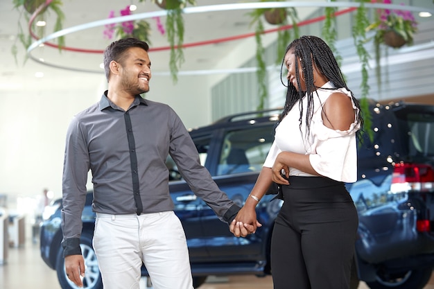 Jovem casal afro-americano escolhe um carro novo em uma concessionária