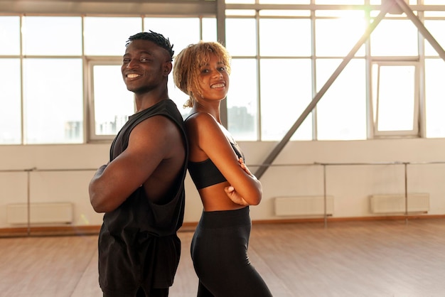 jovem casal afro-americano esportivo em roupas esportivas em pé com os braços cruzados