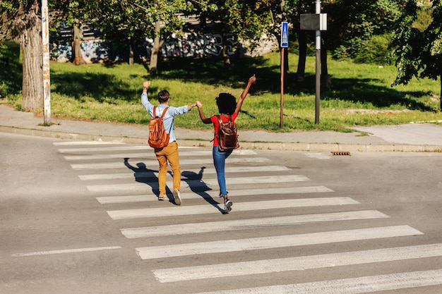 Jovem casal alegre correndo pela rua e sorrindo.