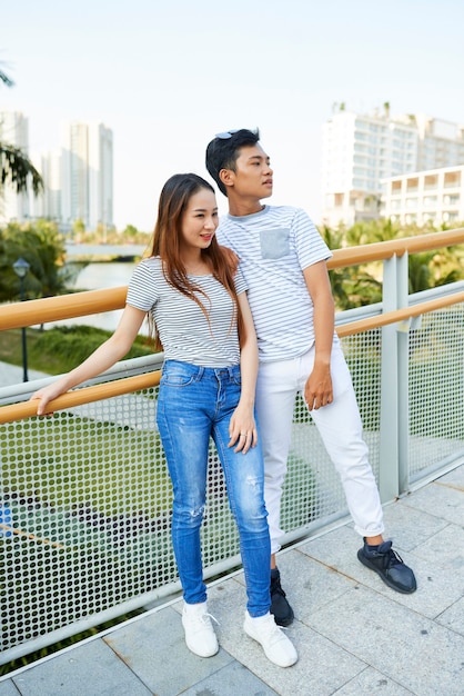 Jovem casal alegre em roupas casuais, em pé na ponte