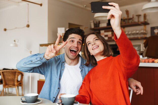 Jovem casal alegre sentado à mesa de um café