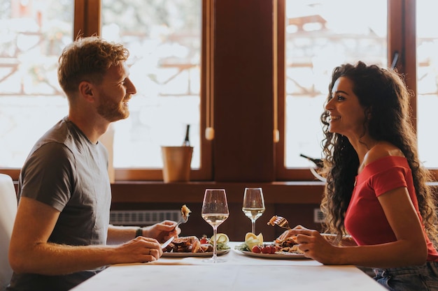 Jovem casal almoçando com vinho branco no restaurante