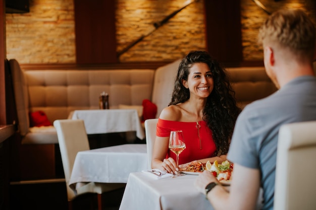 Jovem casal almoçando com vinho branco no restaurante