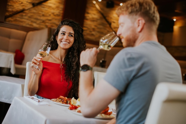 Jovem casal almoçando com vinho branco no restaurante