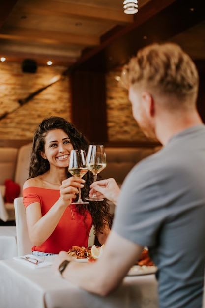 Jovem casal almoçando com vinho branco no restaurante