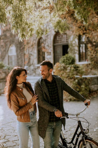 Jovem casal andando com bicicleta no parque outono