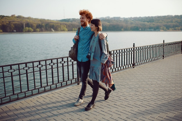 Foto jovem casal andando despreocupado no parque perto do lago