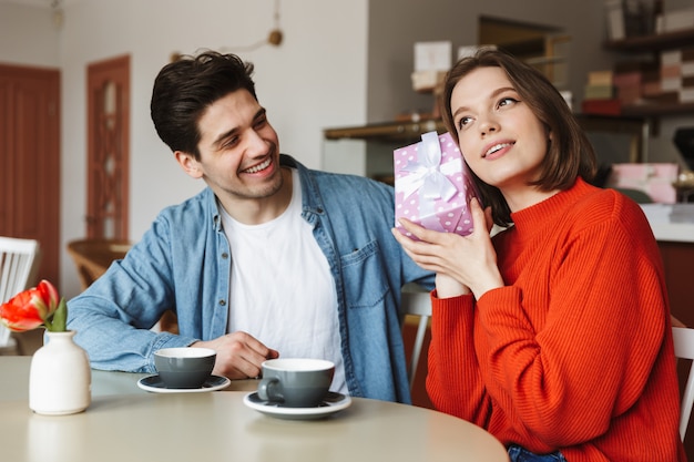 Jovem casal animado sentado à mesa do café