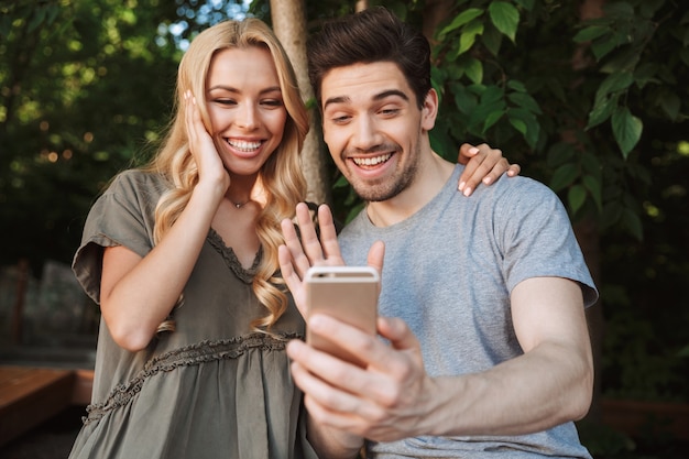 Jovem casal animado tirando uma selfie junto