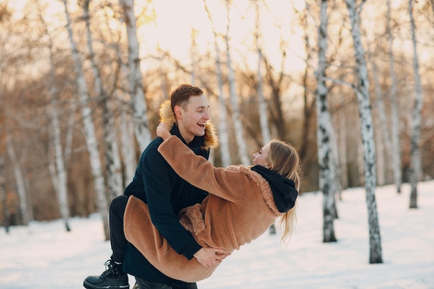 Jovem casal apaixonado andando, brincando e se divertindo no parque florestal de inverno