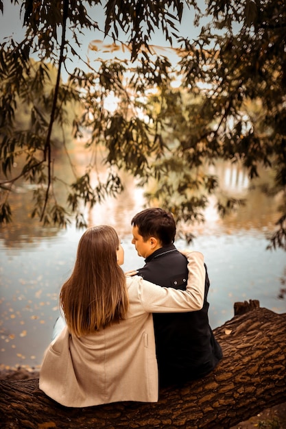 Foto jovem casal apaixonado ao ar livre retrato sensual deslumbrante de um jovem casal elegante e elegante vista de trás no parque no outono perto do lago