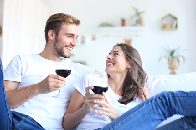 Jovem casal apaixonado bebendo uma taça de vinho tinto na sala de estar.