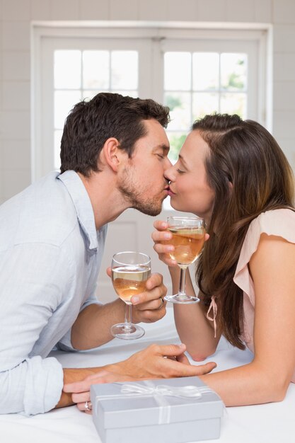 Jovem casal apaixonado beijando com taças de vinho
