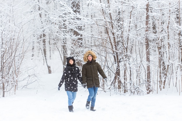 Jovem casal apaixonado caminha no bosque nevado. Férias de inverno ativas.