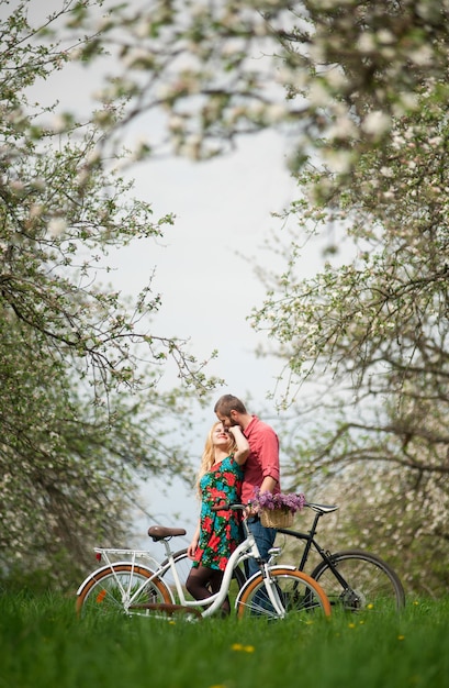 Jovem casal apaixonado com bicicletas no jardim primavera