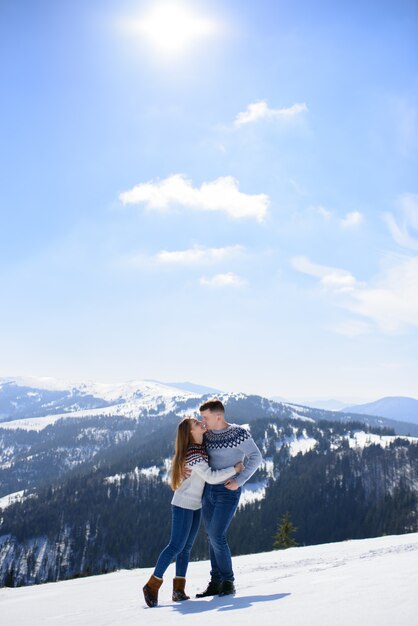 Jovem casal apaixonado em um encontro no topo de uma montanha coberta de neve