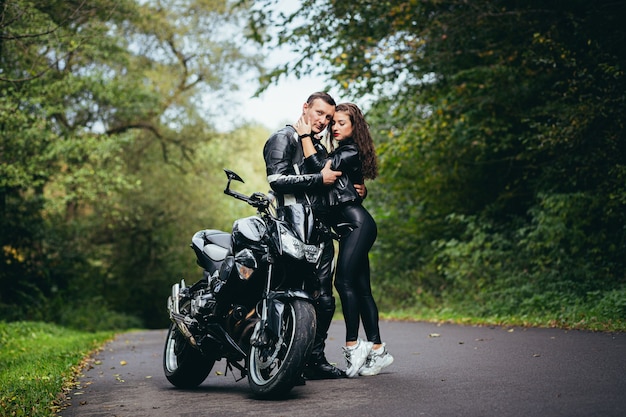 Foto jovem casal apaixonado em uma motocicleta na estrada na floresta