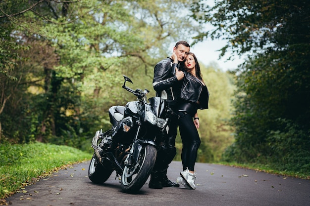 jovem casal apaixonado em uma motocicleta na estrada na floresta