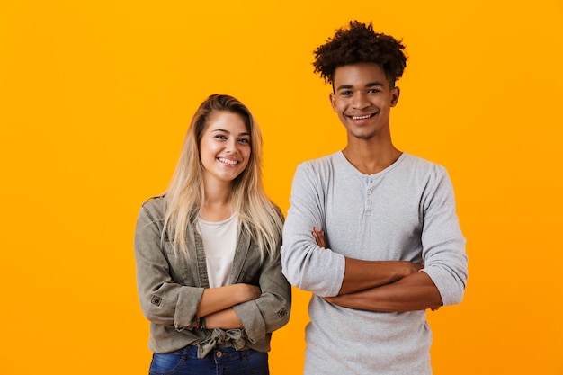 Jovem casal apaixonado feliz posando isolado na parede amarela