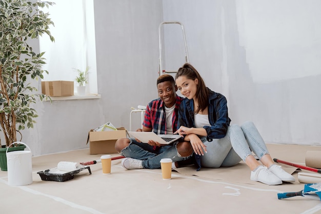 Jovem casal apaixonado passando tempo em novo apartamento redecorando paredes de pintura de quarto