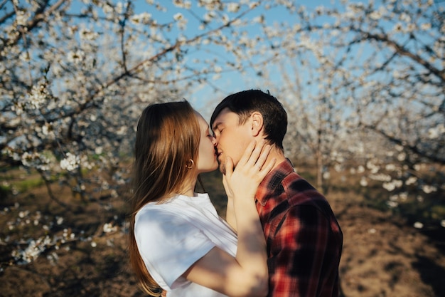 Foto jovem casal apaixonado quer se beijar perto de árvores de flor branca de primavera.