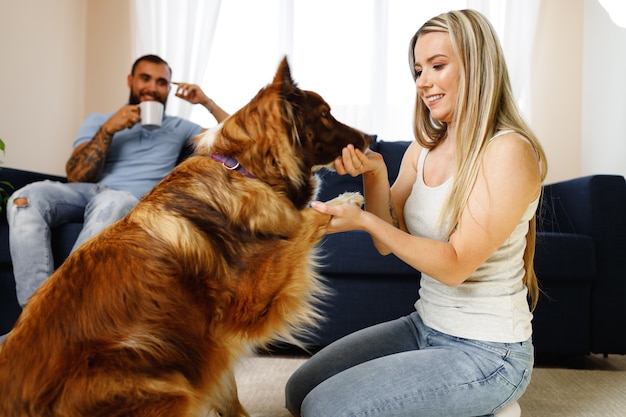 Jovem casal apaixonado relaxando na sala de estar com seu cachorro