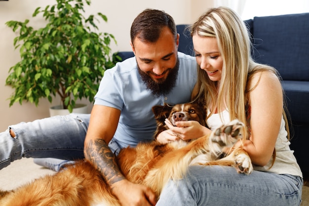 Jovem casal apaixonado relaxando na sala de estar com seu cachorro