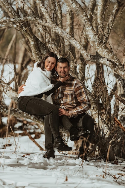 Jovem casal apaixonado sentado em um baú na floresta Roupas frias de inverno História de amor Foco seletivo