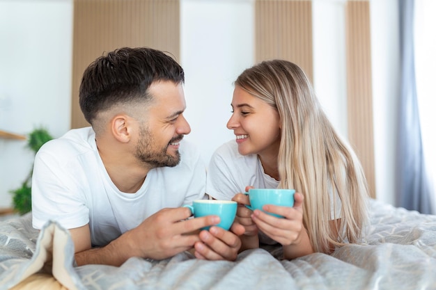 Jovem casal apaixonado tomando café na cama Bom dia Café da manhã saudável na cama Jovem lindo casal apaixonado está tomando café na cama